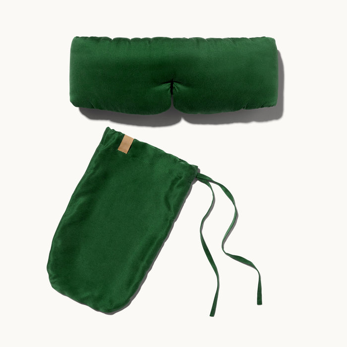 The Arey x Lunya Silk Sleep Mask by Arey, shown in green with a matching drawstring pouch laid flat on a light background, makes an ideal addition to your beauty routine accessory collection.
