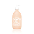 A clear glass bottle with a pump dispenser, labeled in white text, containing exfoliating liquid soap.