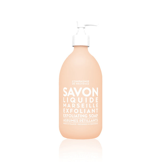 A clear glass bottle with a pump dispenser, labeled in white text, containing exfoliating liquid soap.