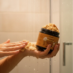 Woman applying body scrub in shower with cookie butter scented exfoliant jar