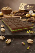 Chocolate bar with green pistachio filling, surrounded by pistachios and chocolate pieces.
