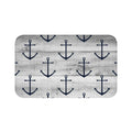 A rectangular gray memory foam mat with a blue anchor pattern against a gray wood plank background and anti-slip backing.