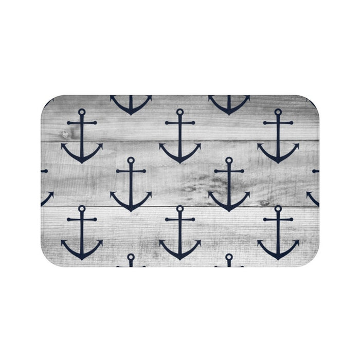 A rectangular gray memory foam mat with a blue anchor pattern against a gray wood plank background and anti-slip backing.