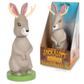 The Jackalope Nodder is a hard vinyl toy designed as a charming Jackalope character, encased in a Western-themed box. It includes an adhesive base for secure placement.
