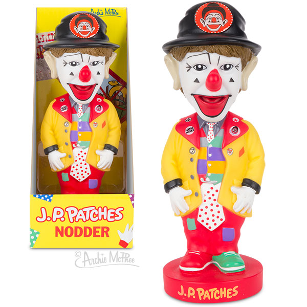 The J.P. Patches Nodder, inspired by the beloved Seattle children's TV show, showcases a yellow coat and colorful clothes, with its packaging box beside it.