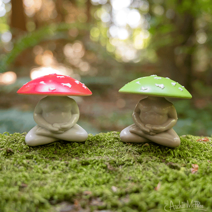 Two Meditating Mushrooms with crimson and emerald caps rest tranquilly on a bed of moss in a peaceful forest scene.