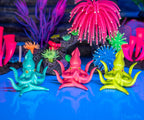 Among a lively coral reef, three Meditating Squids in neon blue, pink, and green float elegantly. These serene mollusks inspire tranquility and reflection as they glide through their aquatic environment.