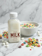 Marshmallow sugar scented body wash bottle with colorful cereal and mini marshmallows on marble