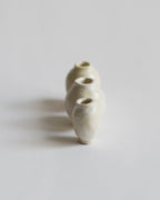 Front facing view of 3 varying mini white glazed mini vases in a straight linefrom the Mini Vase Set - Trio I by Dani Sujin x Nalata Nalata against white-gray background.