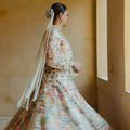 A woman wearing a traditional, floral patterned dress with off-white pearl tassel hair accessory in her hair.