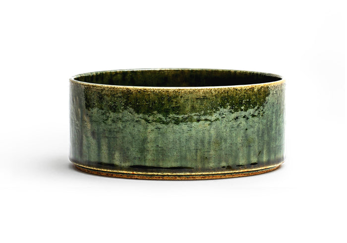 Silhouetted image of ceramic medium oribe bowl with deep green glaze by Time and Style against white background.