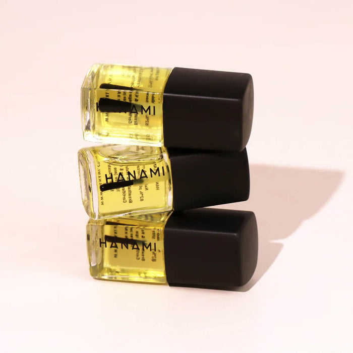 Three bottles of Hanami nail polish with black caps on a light pink background.