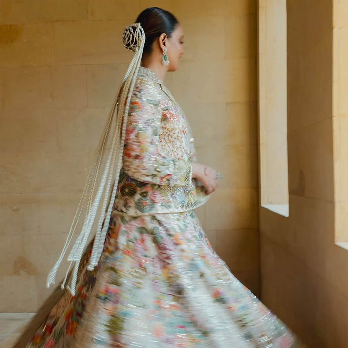 A woman wearing a traditional, floral patterned dress with off-white pearl tassel hair accessory in her hair.