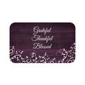 Purple memory foam mat with gentle vines and leaves across the bottom against a wood fence board background with the words "Grateful", "Thankful", and "Blessed" stacked in the center of the mat.