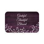Purple memory foam mat with gentle vines and leaves across the bottom against a wood fence board background with the words "Grateful", "Thankful", and "Blessed" stacked in the center of the mat.