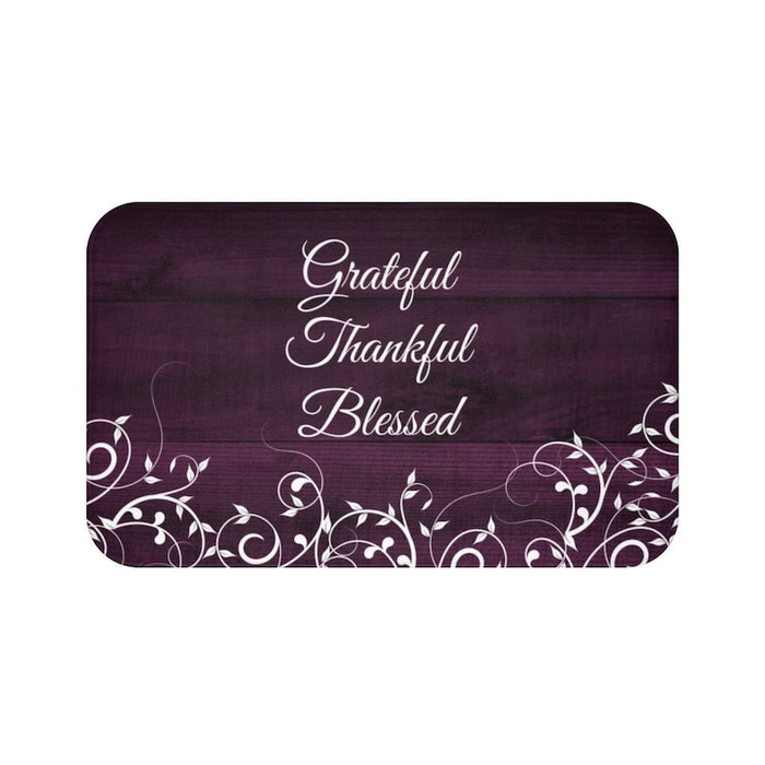 Purple memory foam mat with gentle vines and leaves across the bottom against a wood fence board background with the words "Grateful", "Thankful", and "Blessed" stacked in the center of the mat.