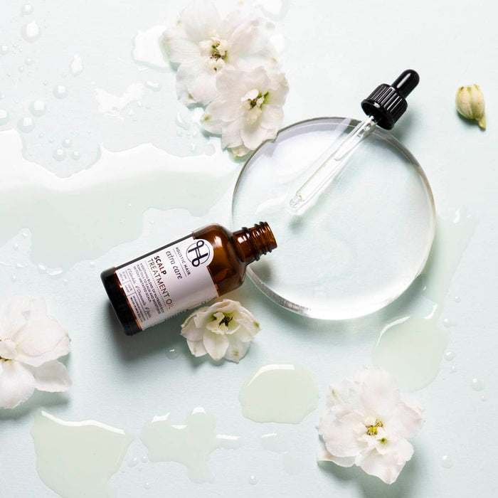 Skincare bottle with dropper and flowers on a white background.