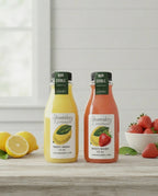 Strawberry and lemon body wash bottles on table with fresh lemons and strawberries.