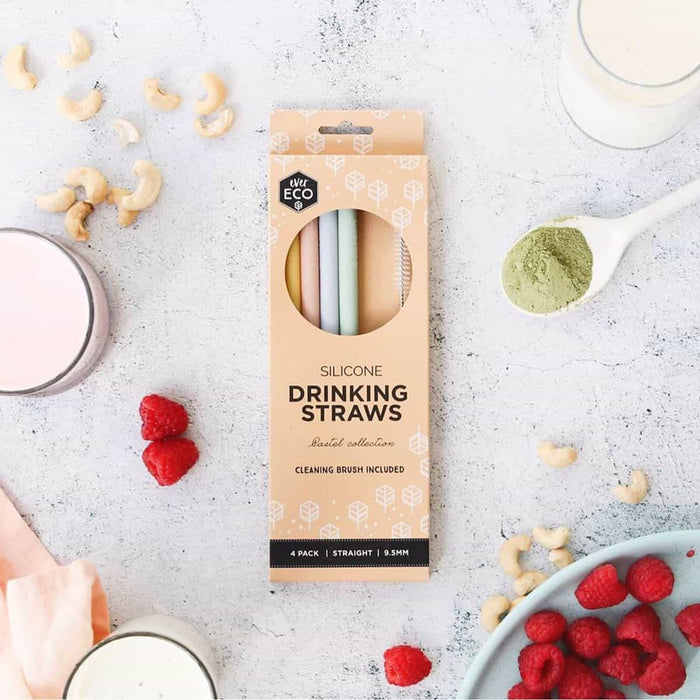 Packaging of silicone drinking straws with a cleaning brush on a kitchen surface with smoothie ingredients scattered around.