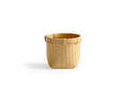 Silhouetted image of small round woven basket by Kohchosai Kosuga against white background.