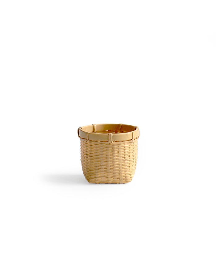Silhouetted image of small round woven basket by Kohchosai Kosuga against white background.