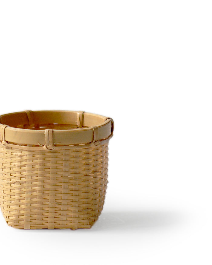 Cropped up-close image of small round woven basket by Kohchosai Kosuga against white background.