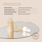 Open bottle of Wildling X Arey serum with dropper resting on a mirror, ingredient list highlighting the formula’s calming, soothing, and redness-reducing effects for skin, all set against a beige background. Specially formulated by Arey as a post-hair dye scalp serum to help reduce redness and calm scalp irritation. Mela-9+ Complex seal is shown.